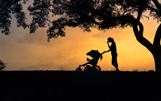 The journey back to intimacy after birth can be tender, emotional, and complex. Here’s how to support your partner after birth — with empathy, patience, and genuine connection. a woman pushing a buggy a dusk